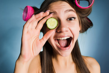 Poster - woman on blue background smiling holding a cucumber slice