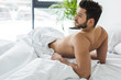 © LIGHTFIELD STUDIOS - bearded shirtless man lying on white bed in the morning