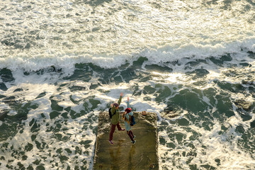 happy young couple standing on the dock among the stormy sea. view from above