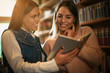 © Mladen - Two young students girl in library reading book.