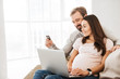 Portrait of a happy young pregnant couple shopping online