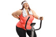 Overweight woman riding an exercise bike and experiencing back pain
