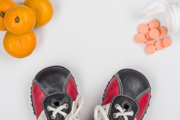 Wall Mural - Vitamin C. Natural citrus and synthetic tablets, choice. White background, children's sneakers