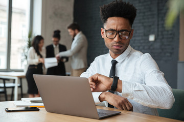 Poster - Concentrated young african businessman looking at watch.