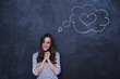 © My Ocean studio - Beautiful smiling young woman at the blackboard with a drawn cloud and heart over her head.
