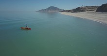 Aerial View Of Young Woman Kayaking Off The Beach And Meeting Another Kayaker With Hat And Flotation Device In Ocean Kayak.