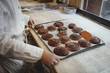 © Maskot - Close up of baker holding tray of buns