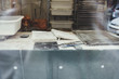 © Maskot - Book on messy table seen through glass at bakery