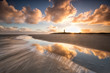dramatic sunrise over North sea coast with lighthouse