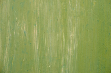  Textured metal surface carelessly colored green paint and faded in the sun in pale gray with rusty specks.