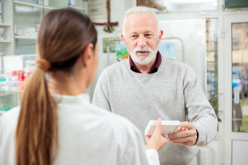 Wall Mural - medicine, pharmaceutics, health care and people concept - happy senior man customer buying medications at drugstore