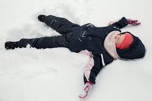 The Kid Is Lying In The Snow On The Ground