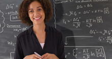 Portrait Of Black Teacher Giving Math Lesson On Chalkboard