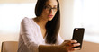 © Mark Adams - A Hispanic woman uses her smart phone at work. A Latina businesswoman browses the web on her mobile phone