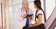 © Mark Adams - An older doctor gives a check up while using her tablet. A young teen gets her throat checked