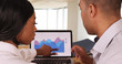 © Mark Adams - Two African American business people looking over figures on laptop and talking about financial graphs and charts. Black businessman and businesswoman team working together