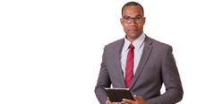 A Black Business Professional Poses For A Portrait With His Tablet And Glasses On A White Background. An African American Executive Stands With His Pad While Adjusting His Spectacles On Blank Backdrop