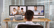 © Mark Adams - Businessman in highrise office talking to colleagues over video conference. Hispanic and Asian group of ethnically diverse group of business professional using computer for VoIP
