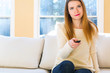 © Tierney - Young woman watching with remote control watching TV in the living room
