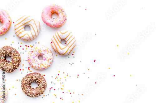 Cuadros en Lienzo Donuts decorated icing and sprinkles on white background top view copy space pat