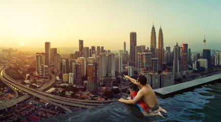 Father and daughter enjoy the beautiful sunrise scene in the open space rooftop swimming pool .