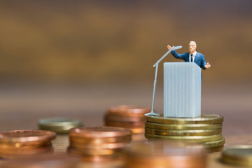 Miniature people : Businessman speaking on the podium