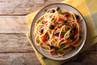 Traditional pasta alla puttanesca with anchovies, tomatoes, garlic and black olives close-up on a plate. horizontal top view