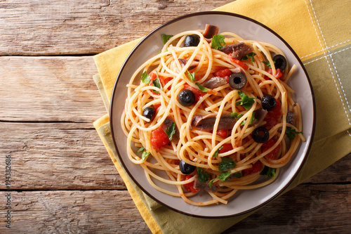 Fotografía Traditional pasta alla puttanesca with anchovies, tomatoes, garlic and black olives close-up on a plate