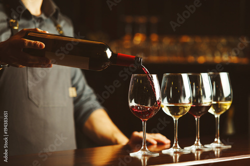 Dekoracja na wymiar  barman-nalewa-czerwone-wino-do-szklanek-na-drewniany-blat-barowy