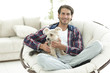 © ASDF - handsome guy with a dog sitting in a large armchair.