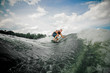 © fesenko - Young man wakesurfing on the board down the river