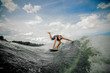 © fesenko - Young and athletic man wakesurfing on the board down the river against the sky