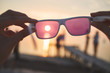 view of the sun, sea and sky through pink sunglasses