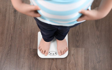 Wall Mural - Overweight boy standing on floor scales indoors