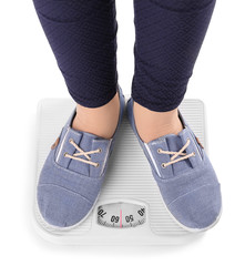 Wall Mural - Overweight girl standing on floor scales against white background