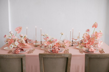 Festive table decor. In pastel pink colors with golden cutlery. With different natural colors roses, peonies, anthurium. Luxury wedding, party, birthday. View from above