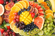 Healthy fruits background in rainbow colours oranges apples grapes pears mango strawberries kiwis on the grey concrete table, top view, selective focus