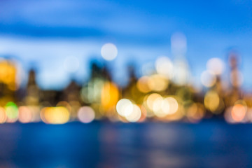 Bokeh of NYC New York City downtown lower financial district Brooklyn Bridge skyscrapers, east river, cityscape skyline during evening dark blue sunset, dusk, twilight