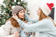 © EdNurg - Women friends during the Christmas party at a party in knitted hats, the concept of friendship and relationships in modern society