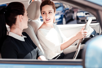 Business wont wait. Occupied young stylish women sitting in the car looking at each other and communicating.