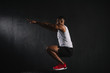 © LIGHTFIELD STUDIOS - side view of young african american sportsman squatting on black