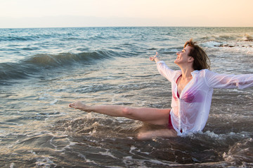 Girl rests and has fun in sea wave at sunset