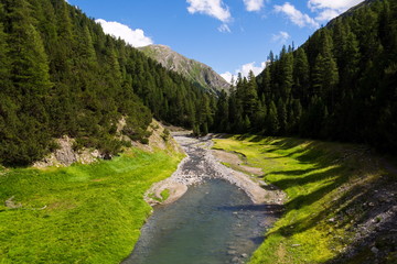 Torrente vallaccia flows into lake Lago di Livigno reservoir on border of Italy and Switzerland, Stelvio National Park, beautiful idyllic landscape