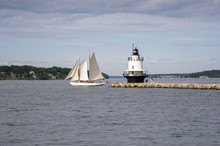 Authentic Schooner Sailboat Sails Past Maine Lighthouse At End Of Stone Breakwater