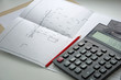 © rannica - The plan is a project of a residential attic house. Red pencil and calculator on a white background