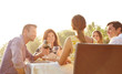 © Trinette Reed/Stocksy - Friends having dinner and wine in a tropical location outdoors
