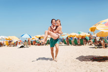 Young Man Carries Woman On Beach