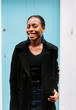 © kkgas/Stocksy - Beautiful African woman standing in frornt of a door to a property.