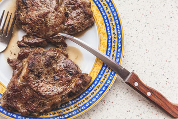 plate with two succulent steaks stands on gray table