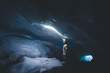 © Christian Tisdale/Stocksy - Young man looking toward the ceiling of an ice cave with his headlamp